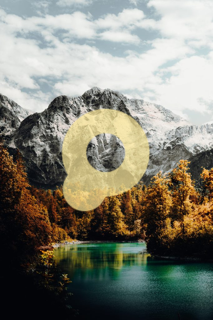 Зеленые и желтые деревья у горы под белыми облаками