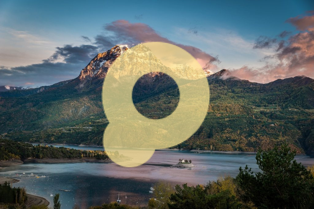 Идиллический снимок огромной горы, покрытой растительностью, у подножия которой находится водоем